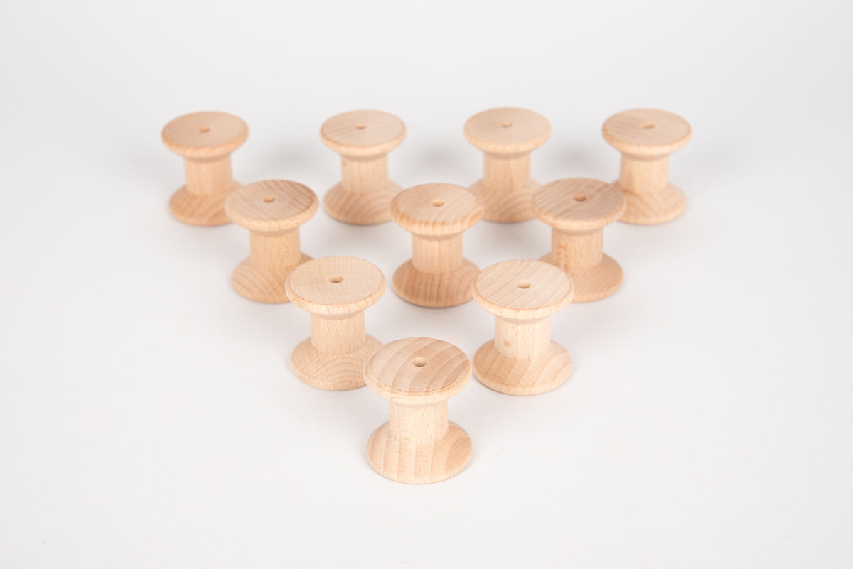 Natural wooden thread spools arranged in a loose cluster, each with a hole.