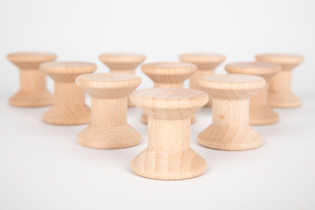 Natural wooden thread spools, round bobbins with central holes, foreground row.