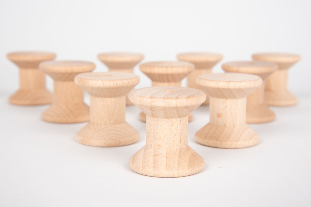Natural wooden thread spools, round bobbins with central holes, foreground row.