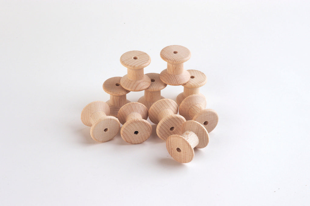 Set of natural wooden thread spools, round bobbins with central holes.