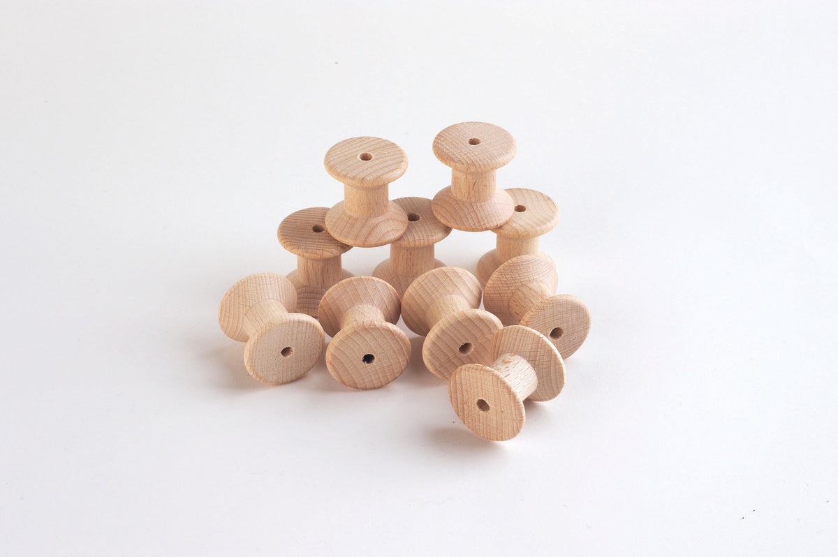 Set of natural wooden thread spools, round bobbins with central holes.