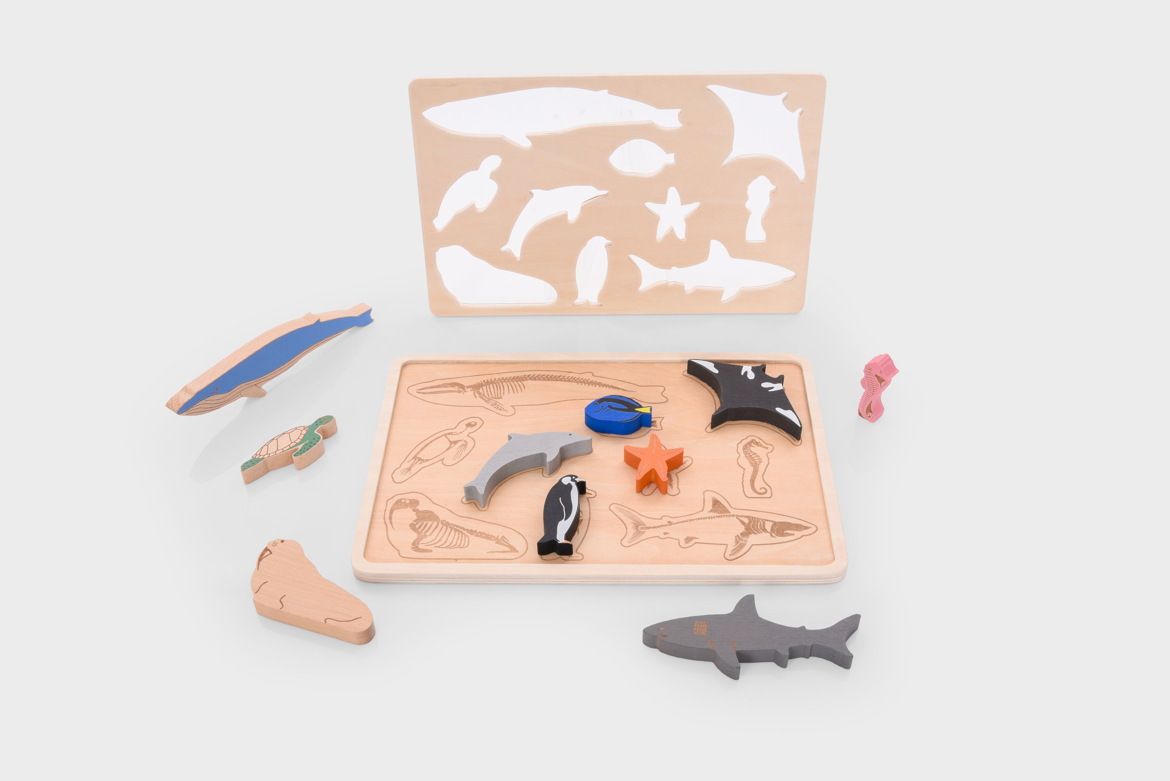 Ocean animal layer puzzle set with wooden base and cutout sea animals in blue, black, pink, and orange.