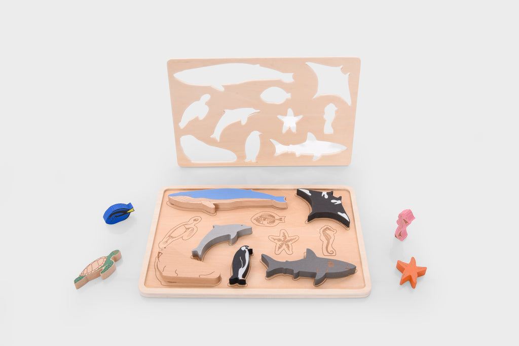 Wooden ocean animal layer puzzle tray with assorted sea animal pieces, including sharks and starfish.