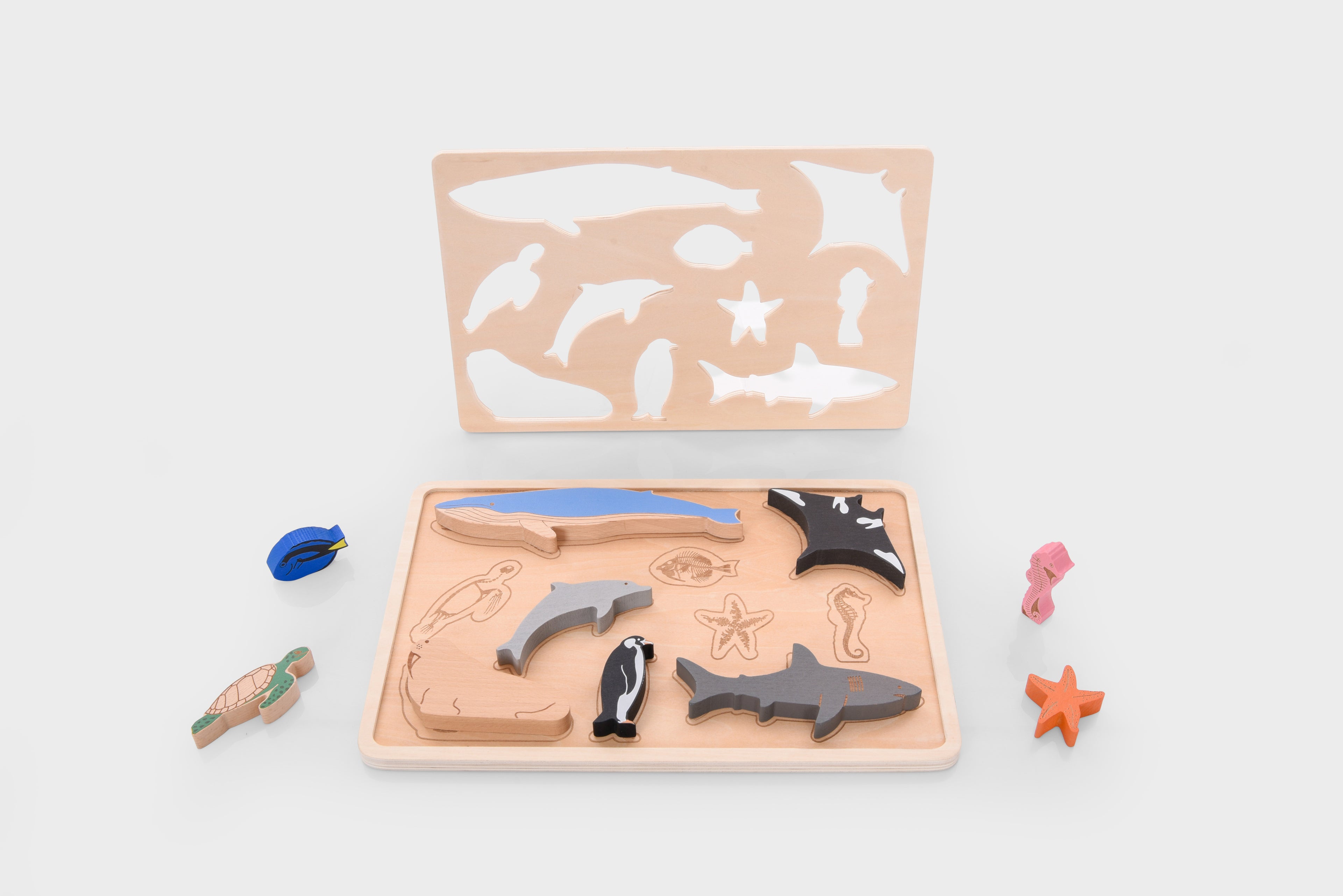Wooden ocean animal layer puzzle tray with assorted sea animal pieces, including sharks and starfish.