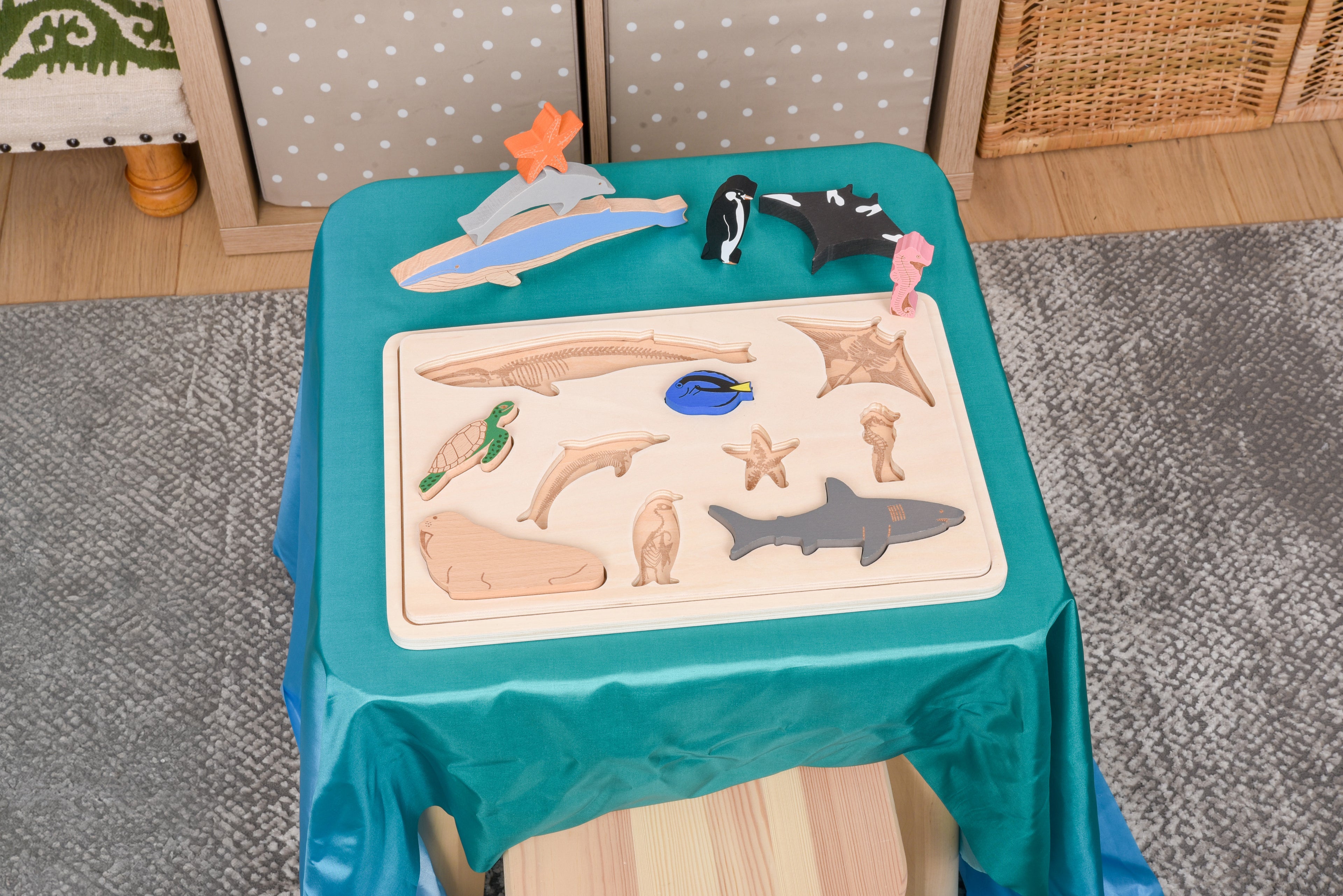 Child-sized ocean animal layer puzzle on teal cloth table with wooden tray and layered ocean animal pieces.