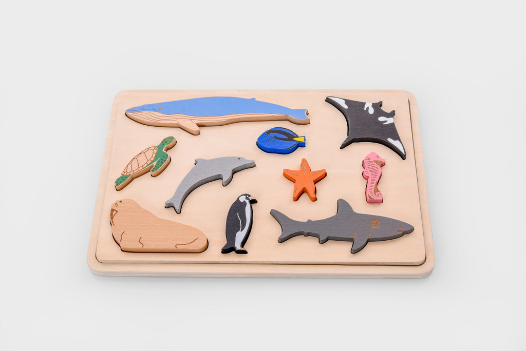 Ocean animal layer puzzle board with sea animal pieces arranged on a light wood tray, including starfish.