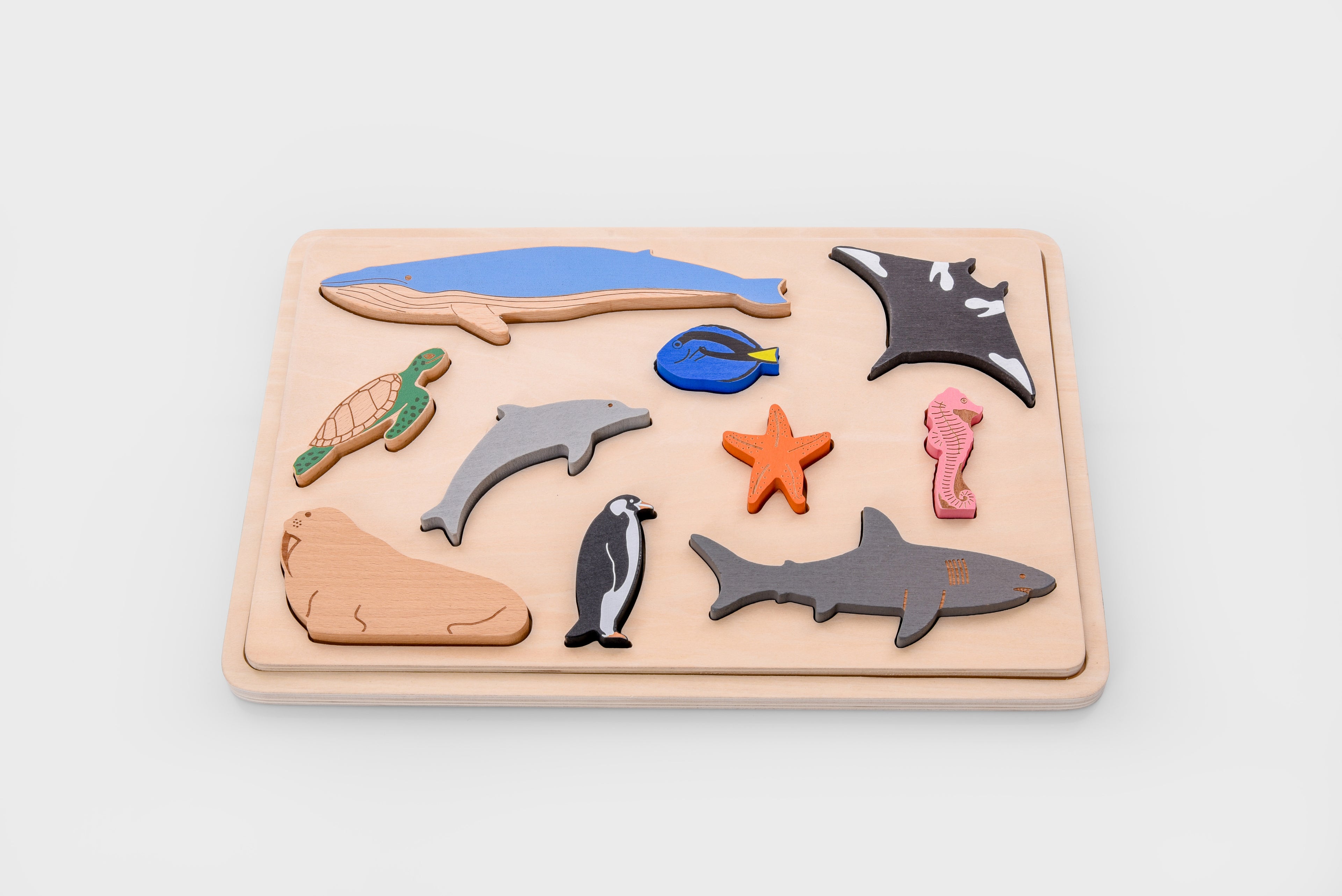 Ocean animal layer puzzle board with sea animal pieces arranged on a light wood tray, including starfish.