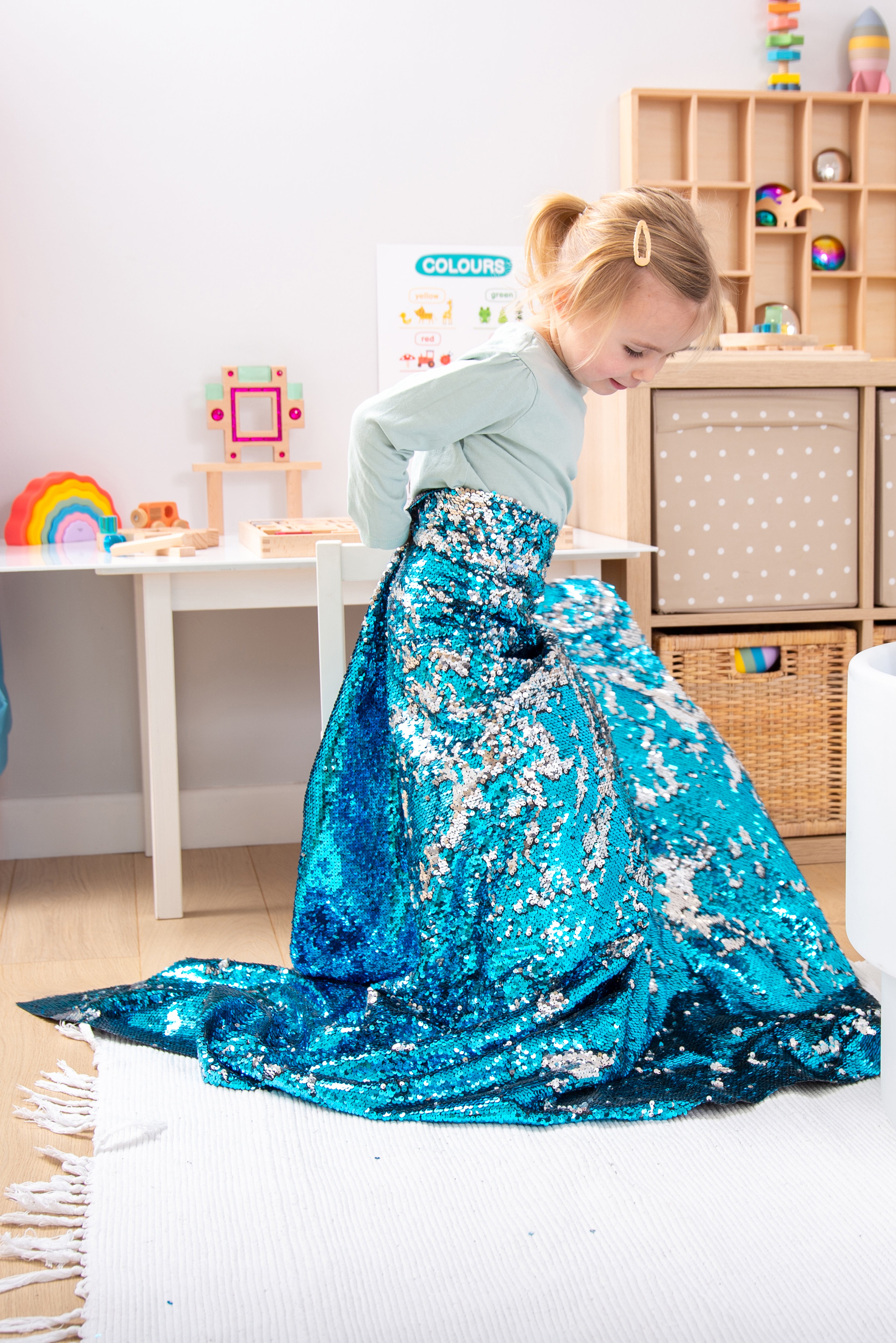 Blue sequin fabric blanket draped around a child, with glittery surface