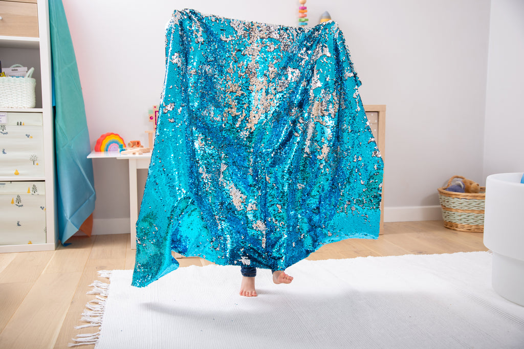 Blue sequin fabric draped blanket with sparkly, uneven shimmer pattern