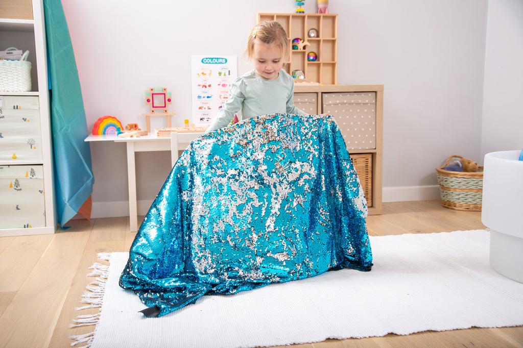 Blue shimmering sequin fabric draped as a blanket, held by a child