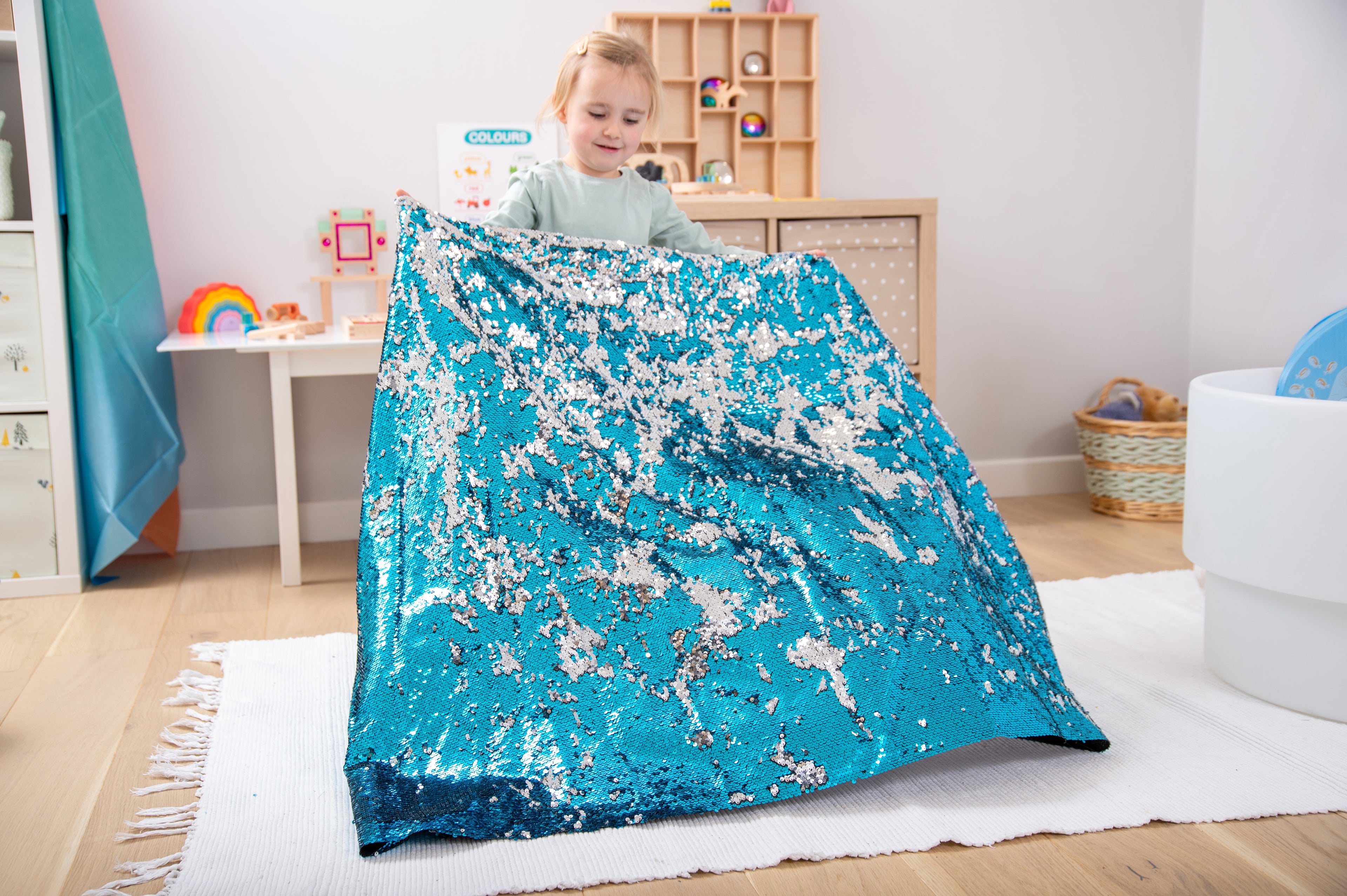 Blue sequin fabric blanket spread across the floor, held by a child