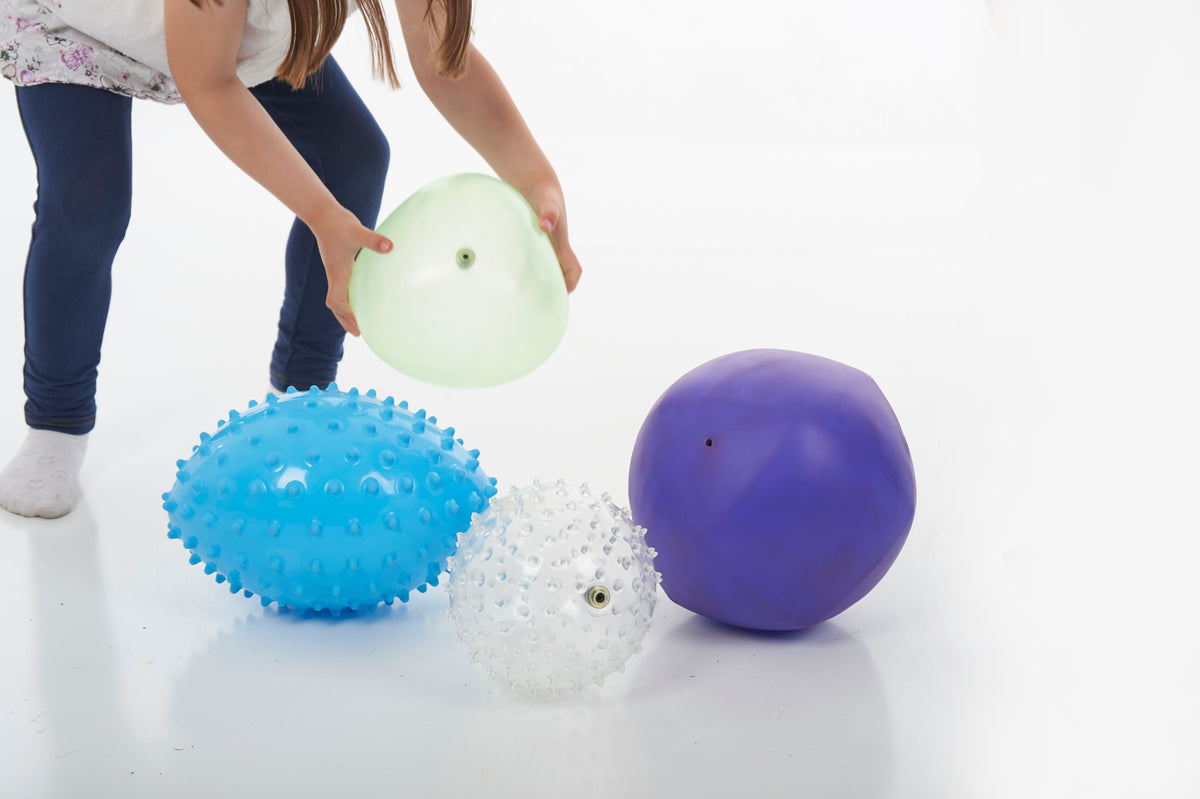 Sensory balls on floor: blue spiky, white speckled, light green and purple smooth
