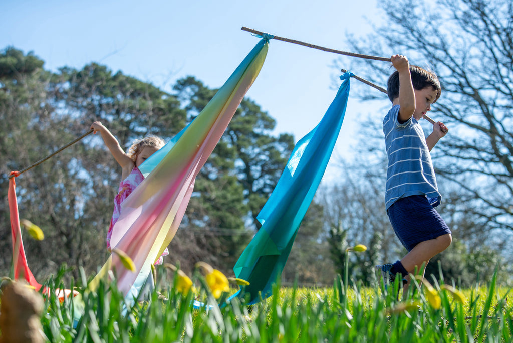 Ombre fabric ribbon scarves in green, yellow, pink, and blue, flying outdoors