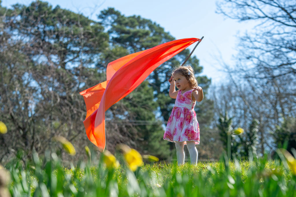 Ombre fabric ribbon scarf in orange-red with pink and teal, lifted overhead