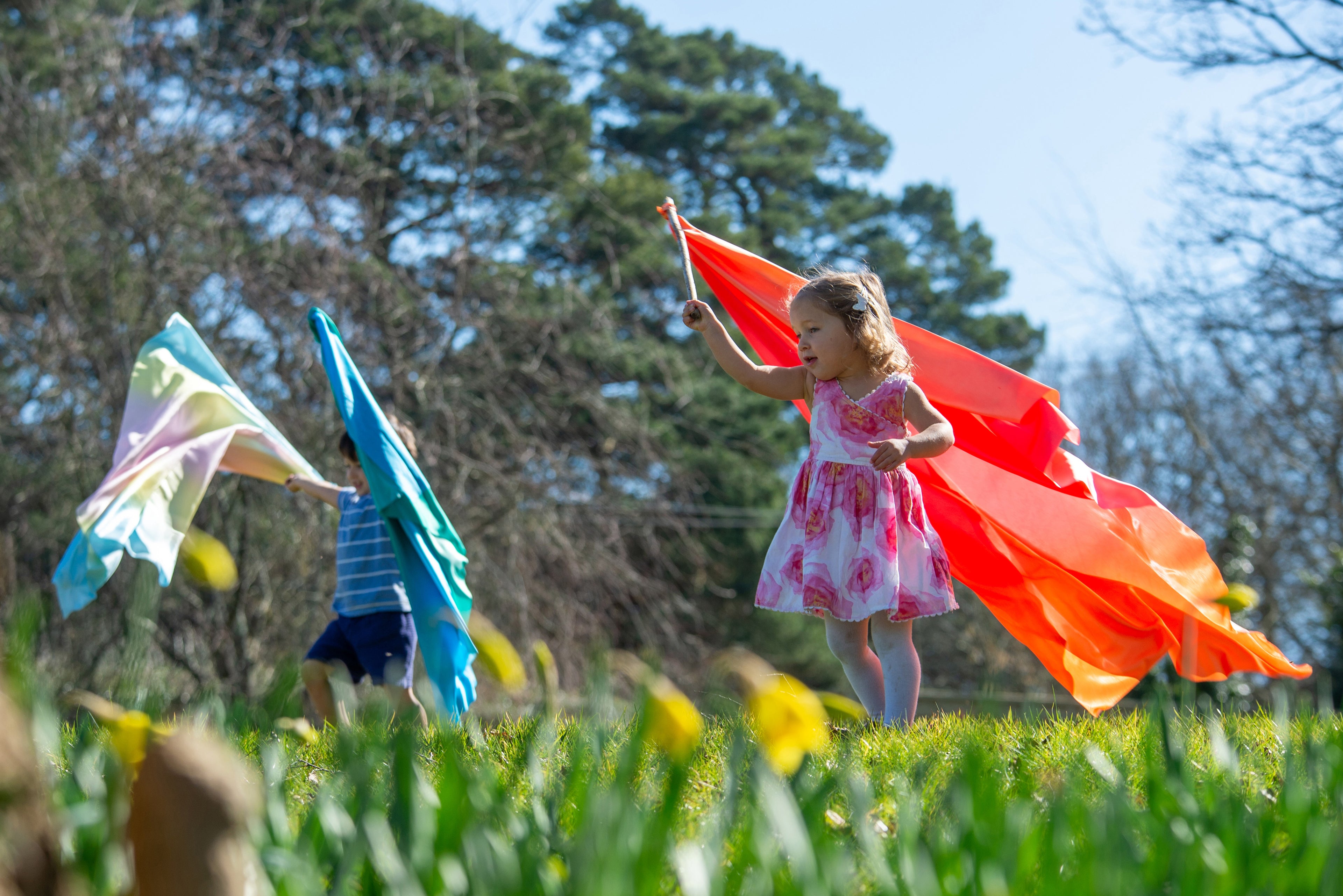 Orange-red ombre fabric ribbon scarf overhead, with teal and green pieces behind