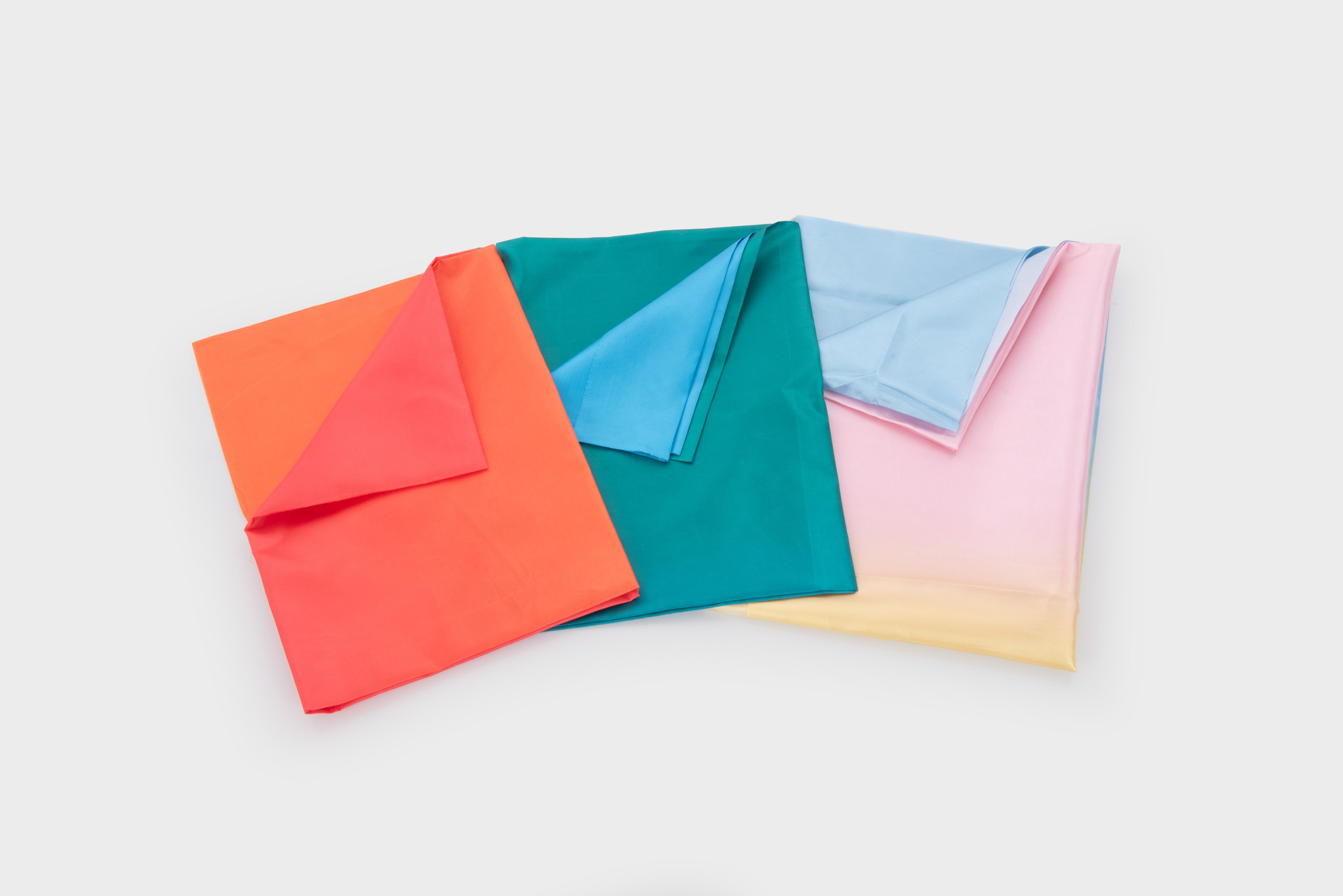 Ombre fabric swatches in coral, teal, blue, and pink ombre, folded squares