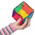 Colorful hinged cube puzzle with multicolor plastic panels, held in hands
