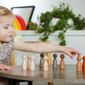 Wooden peg people set with assorted light and dark figures on a tabletop.