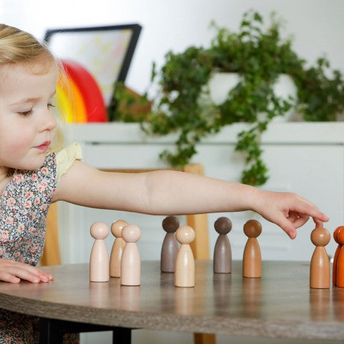 Wooden peg people set with assorted light and dark figures on a tabletop.