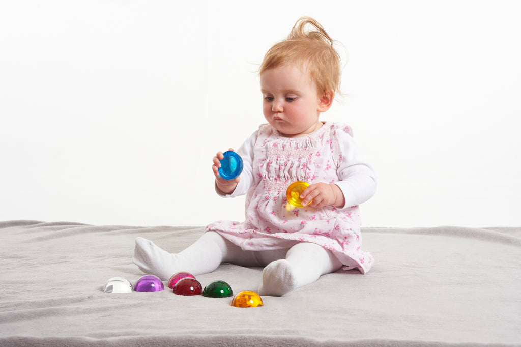 Baby toy set of 8 colorful hemispheres on a gray blanket