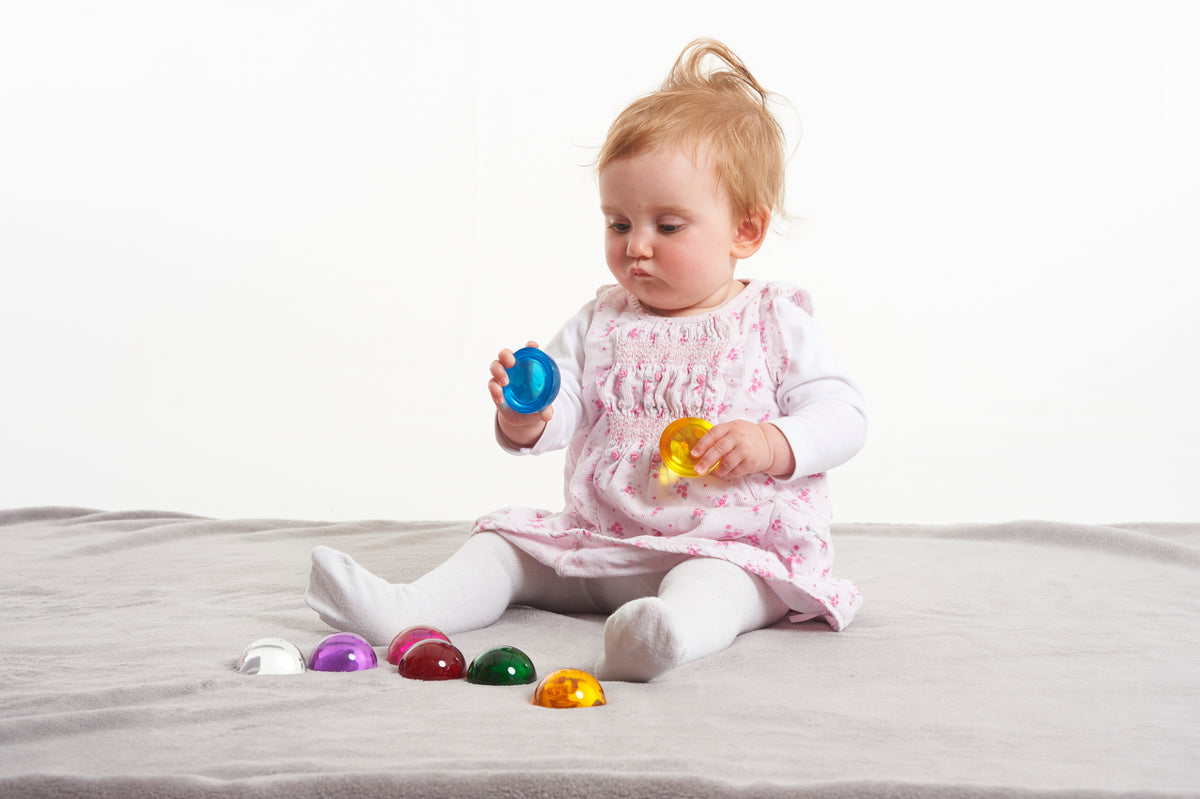 Baby toy set of 8 colorful hemispheres on a gray blanket