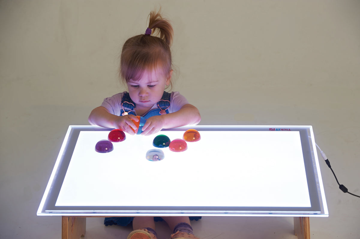 Set of 8 colorful light-up hemispheres scattered on a glowing play tray