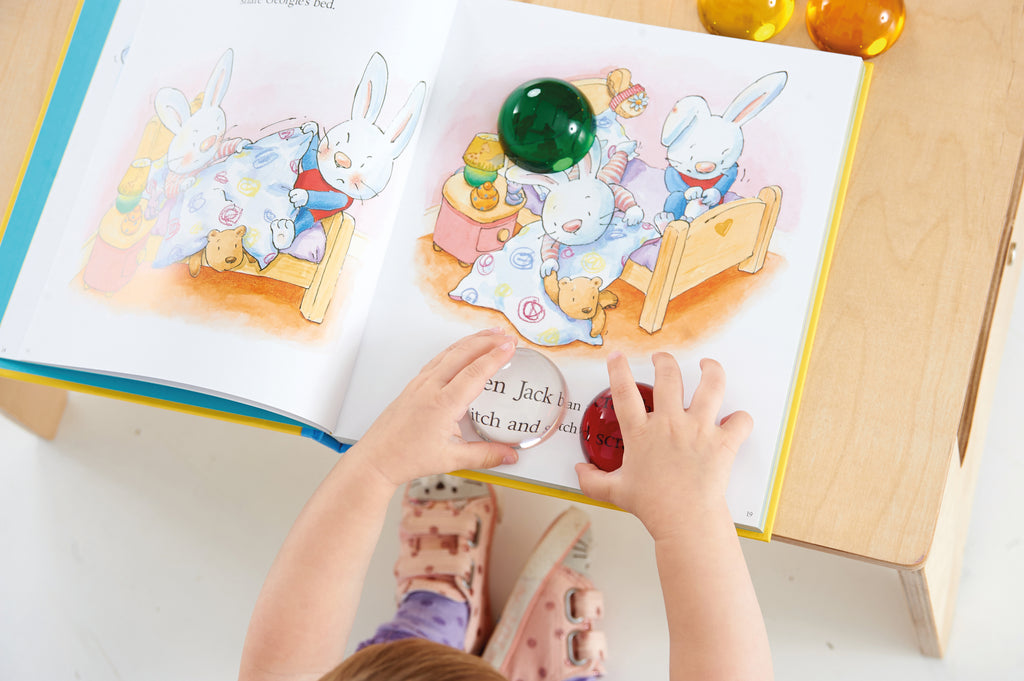 Child hand playing with colorful hemispheres on an open activity book