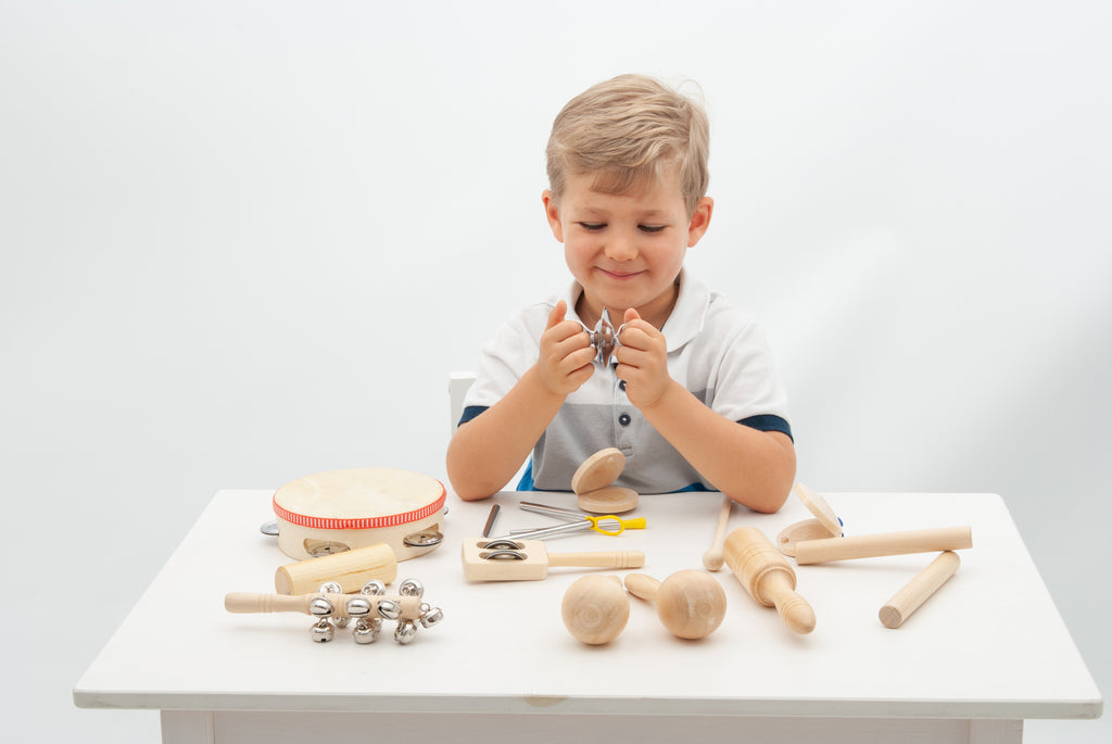 Wooden percussion set with drum, shakers, cymbals, and mallets on table