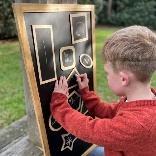 Wooden shape activity board with geometric cutouts and cards, child hand pressing pieces