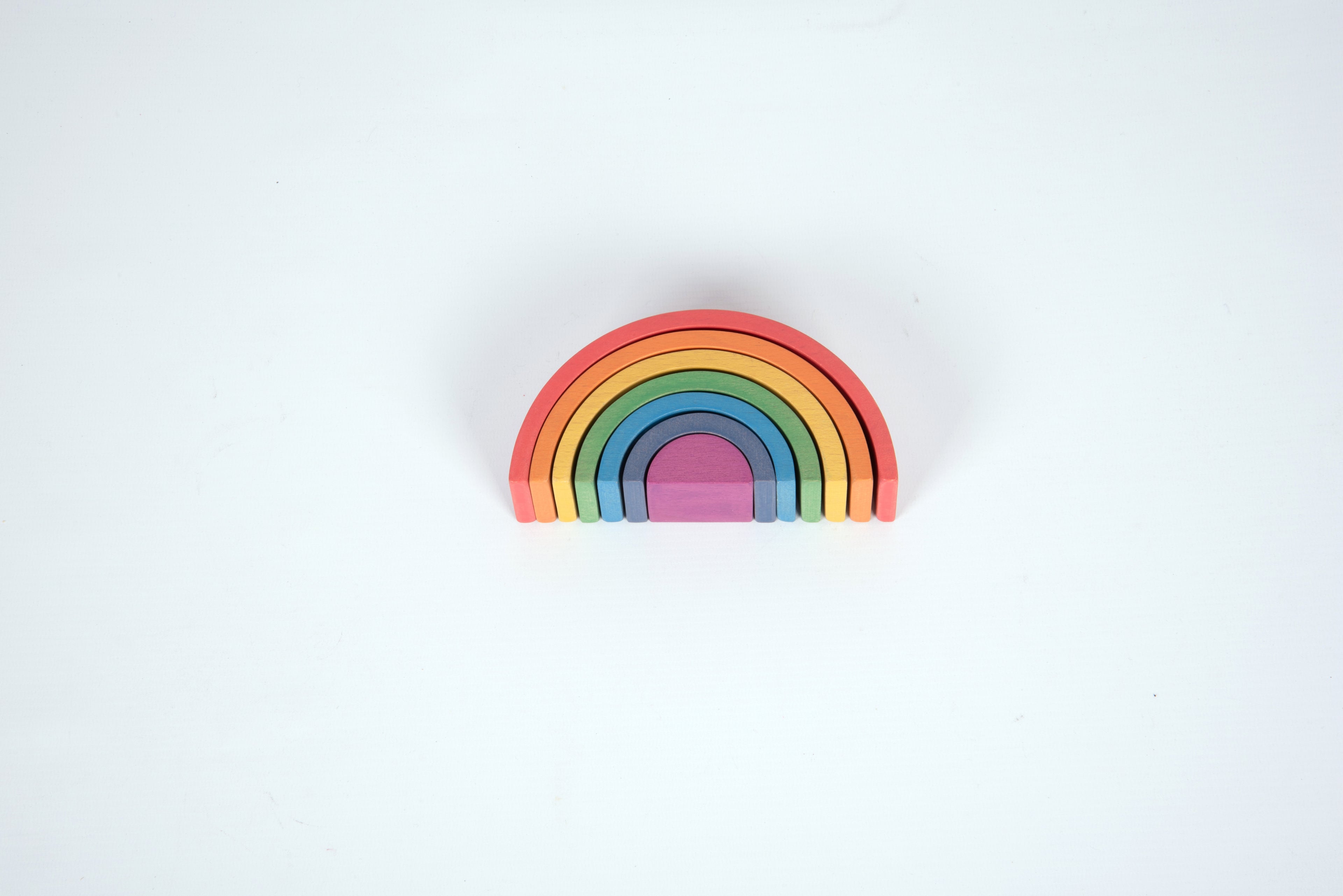Small rainbow arch toy with layered curved arcs in red, orange, yellow, green, blue, and purple
