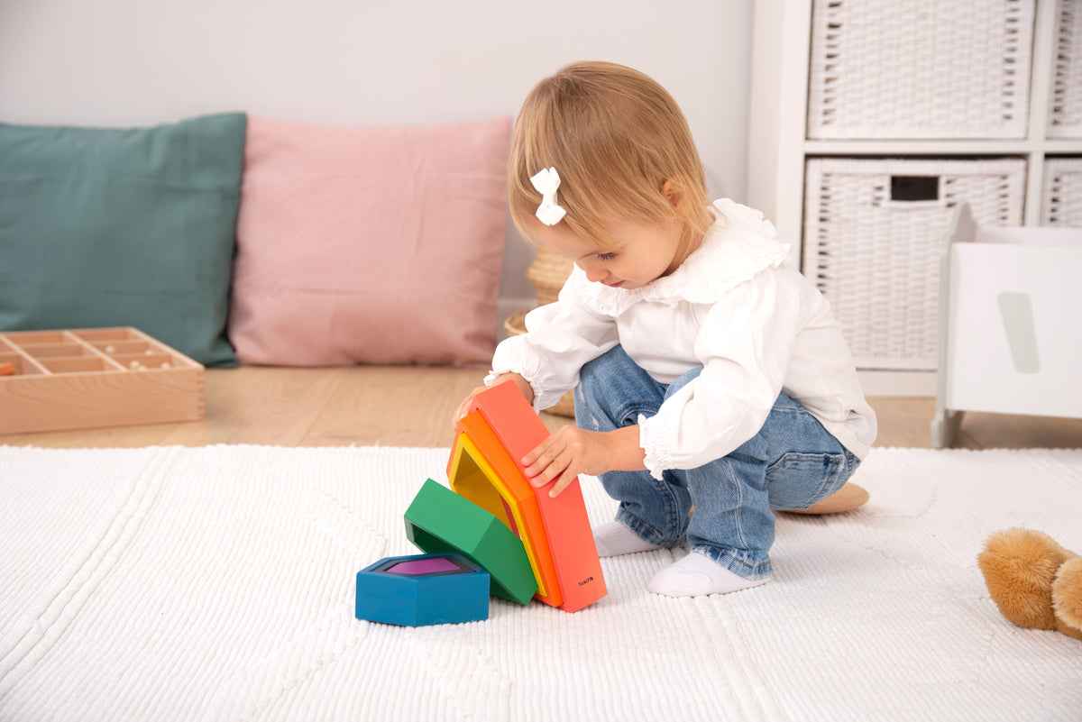Toddler holding rainbow house nesting blocks with stacked colored frames