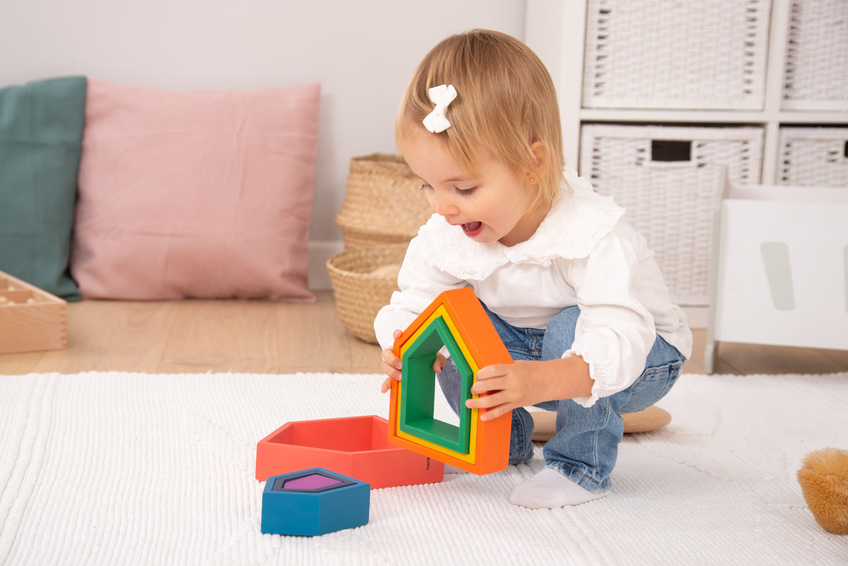 Toddler playing with rainbow house block stack with nested colored frames