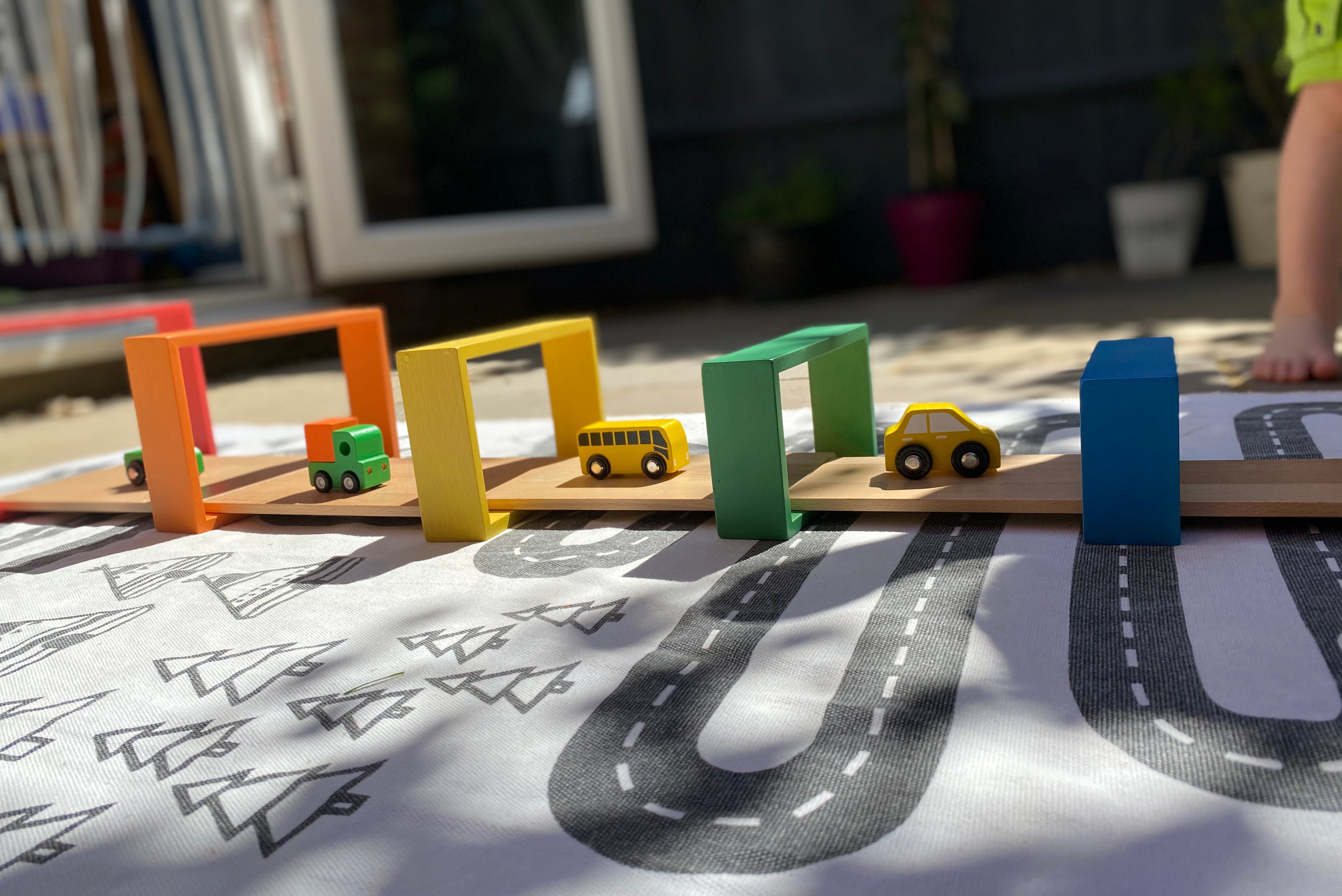 Colorful rectangular frame blocks with toy vehicles on a patterned play surface