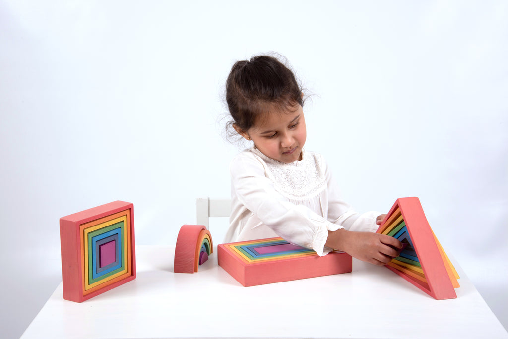 Child playing with rainbow framed foam building blocks and curved arch piece