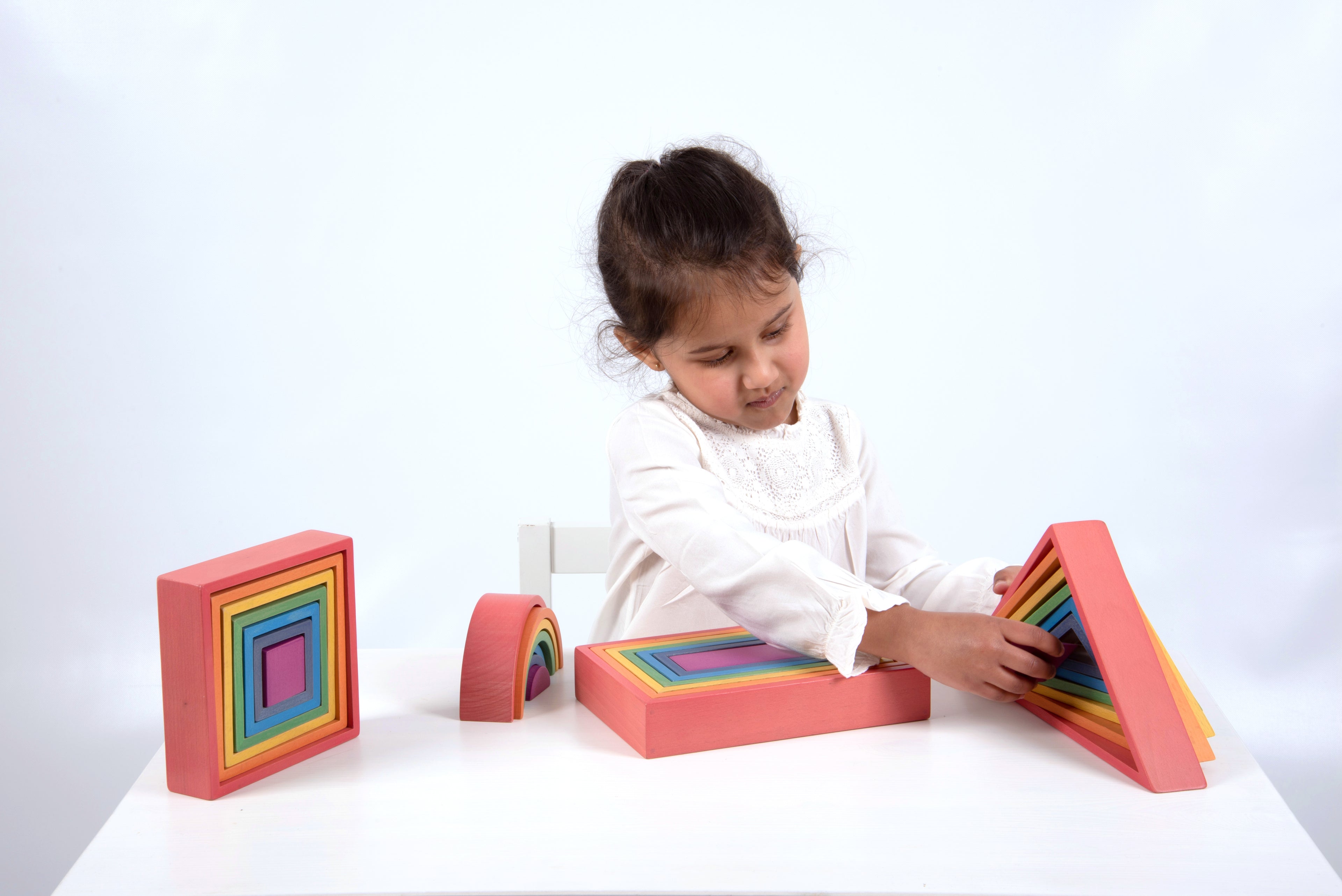Child playing with rainbow framed foam building blocks and curved arch piece