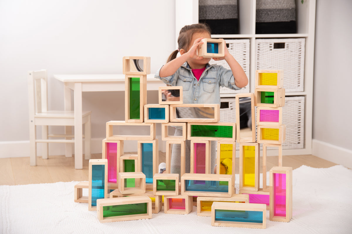Kid playing with wooden rainbow window bricks stacked into a house-like tower