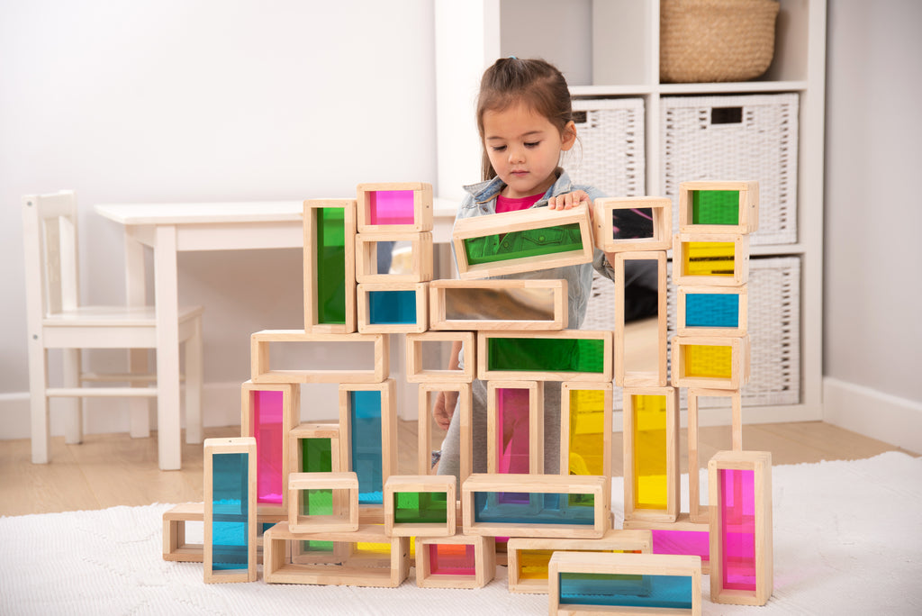 Wooden rainbow building blocks with colored inserts stacked into tall play structure