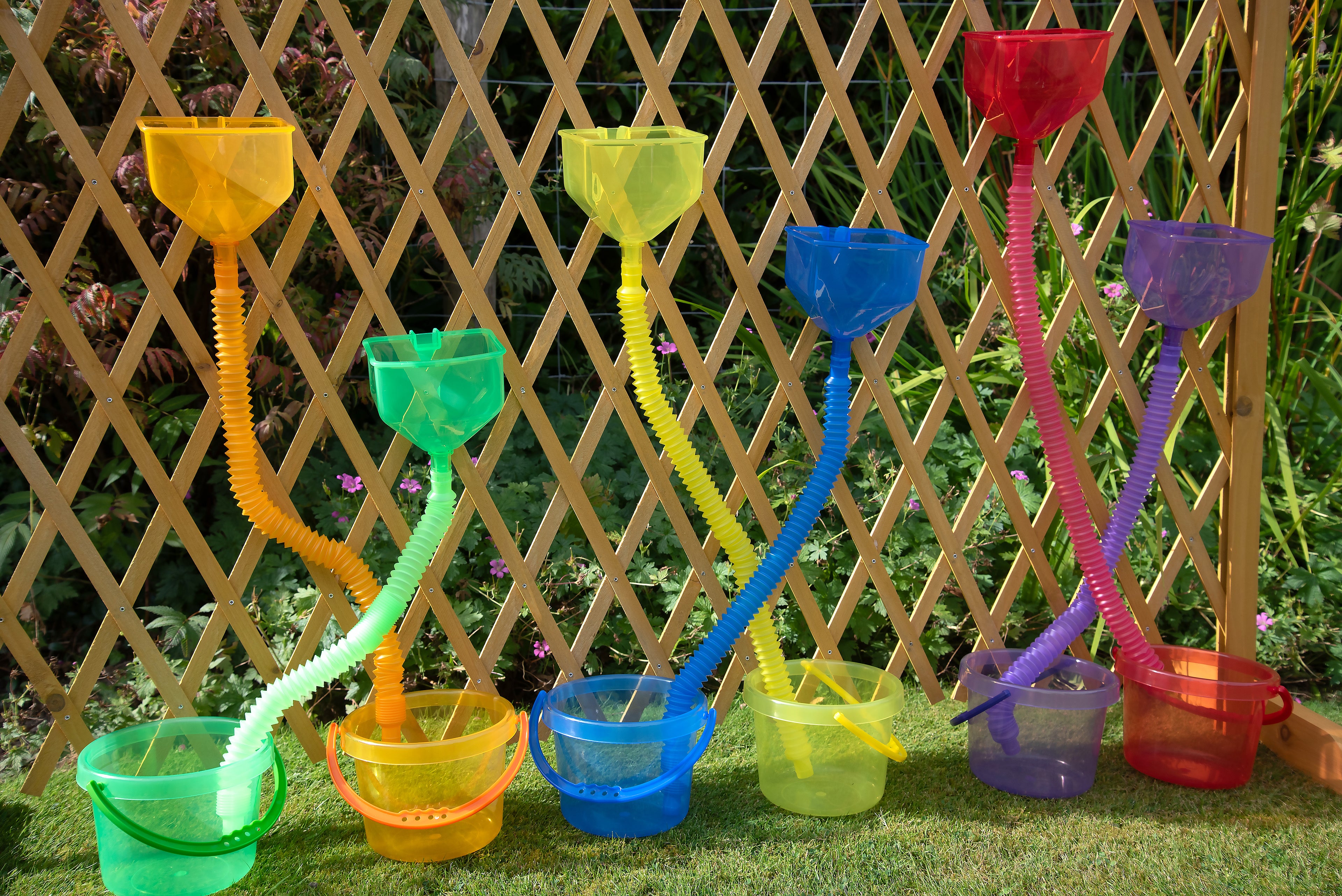 Close-up of colorful flexible tube sprayers with attached scoop cups on a lattice frame