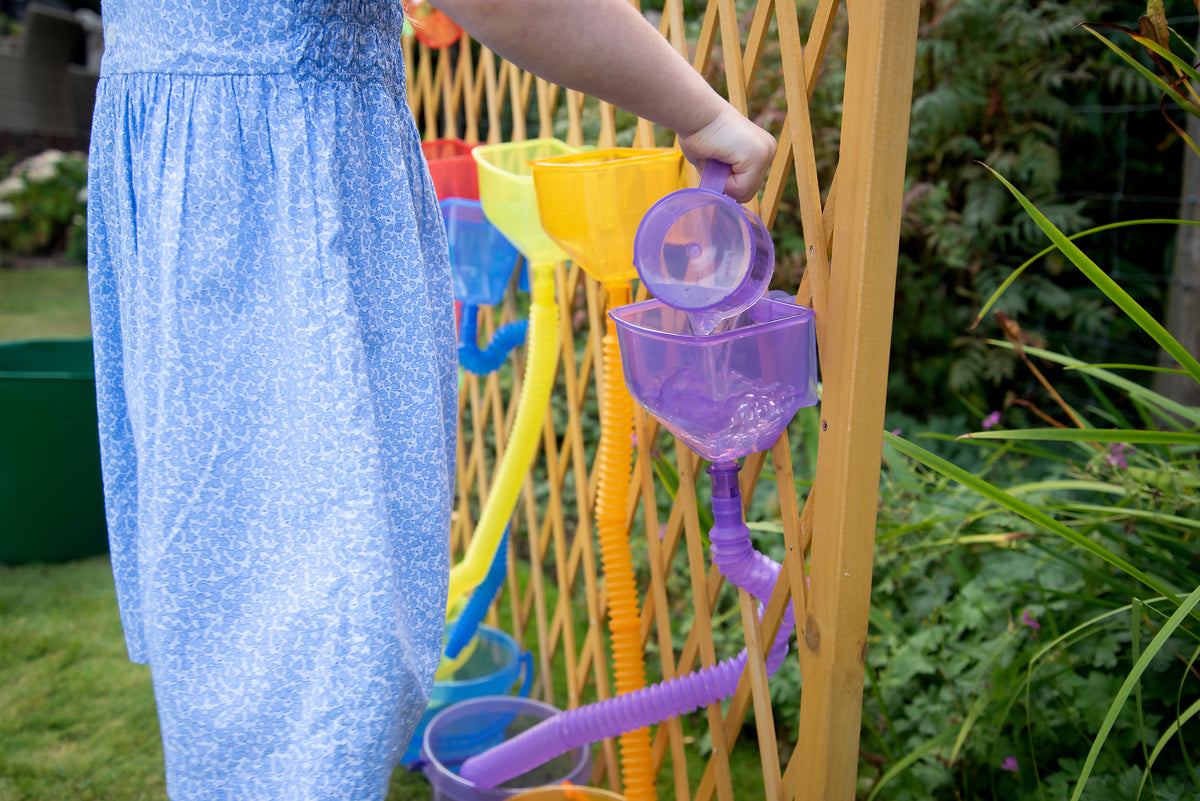 Purple flexible water tubes with scoops mounted on a wooden outdoor frame