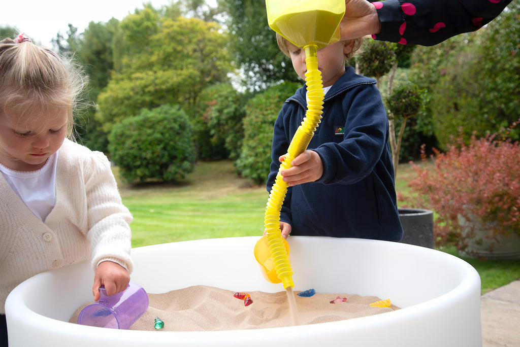 Yellow flexible ribbed tube with spiral nozzle, used as an outdoor water sprinkler