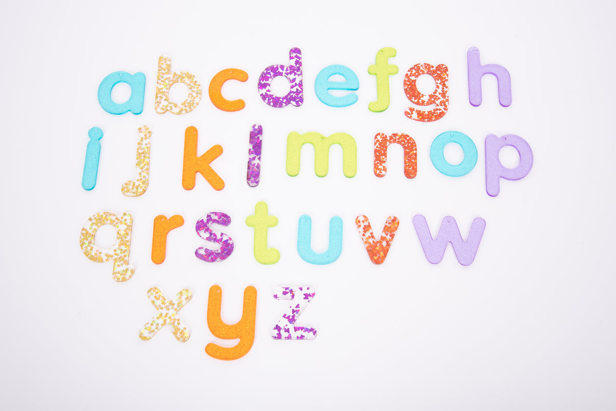 Colorful glitter alphabet letter cutouts arranged on a white background