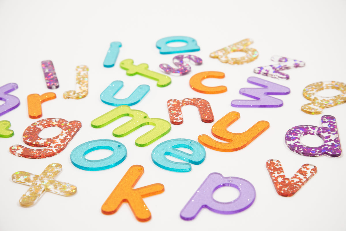 Colorful glitter alphabet letter cutouts scattered on a white background
