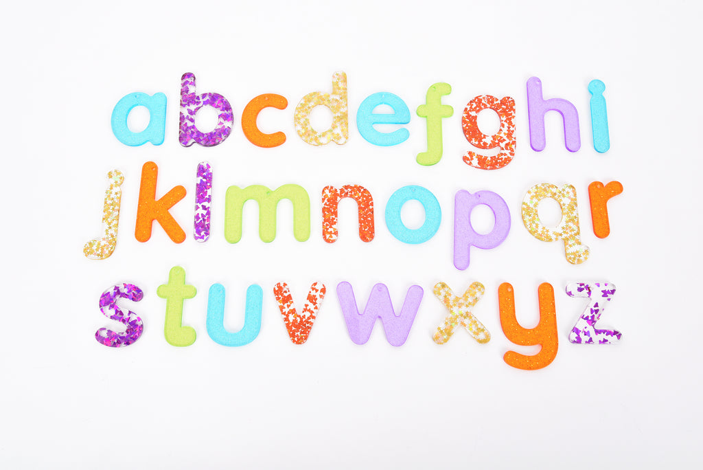Colorful glitter alphabet letter cutouts arranged on a white background