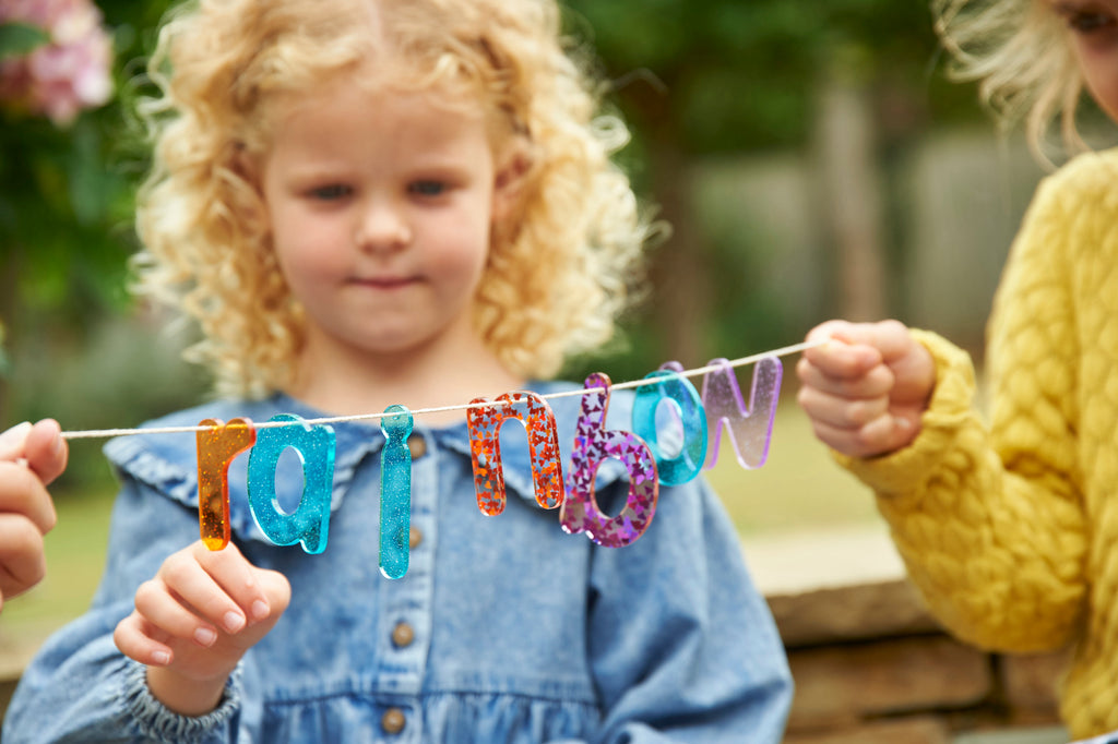 Colorful glitter letter banner with rainbow number letters held by a child