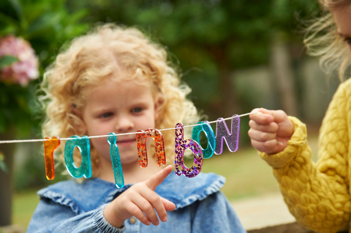 Colorful glitter letter banner with rainbow number letters held in hands by a child