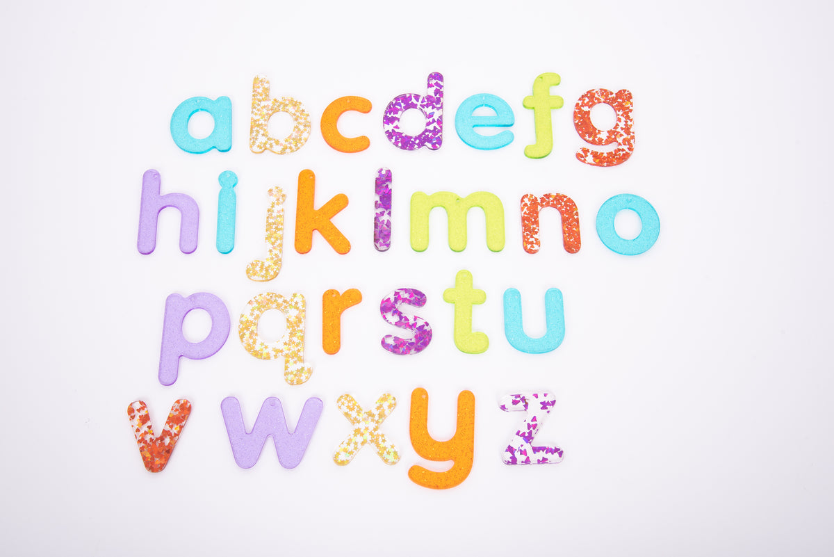 Colorful glitter alphabet letter cutouts arranged on a white background