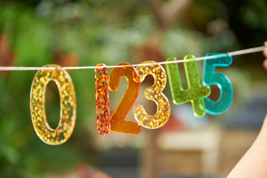 Rainbow glitter number banner with gold, orange, green, and blue digits 0 2 3 4 5
