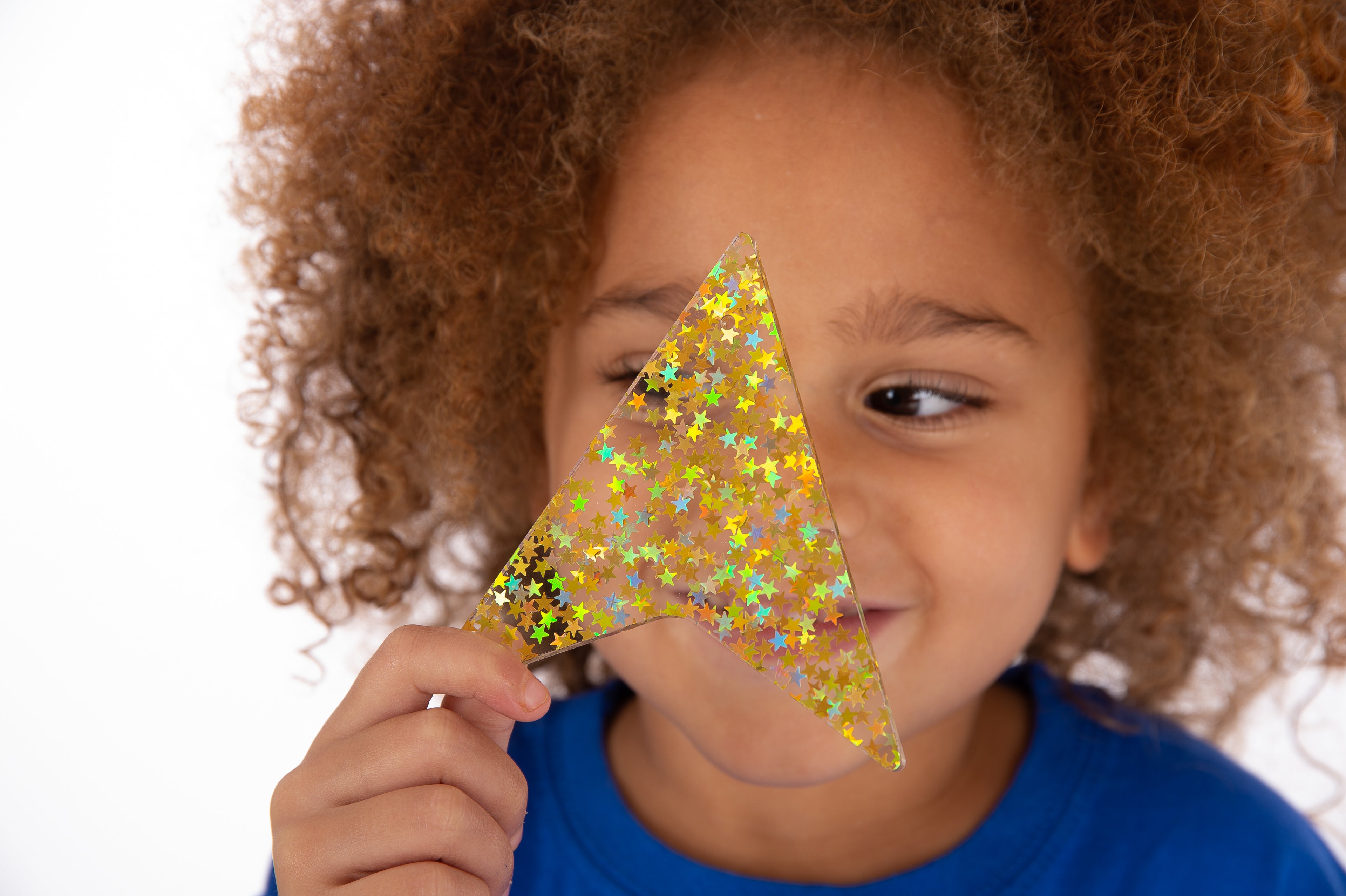 Child holding a gold glitter star shape close-up, curly hair and blue shirt visible