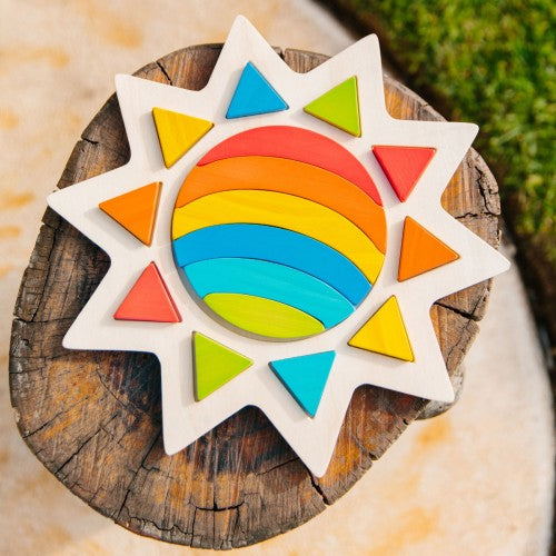 Rainbow sun wall decoration with multicolor triangular rays on white backing