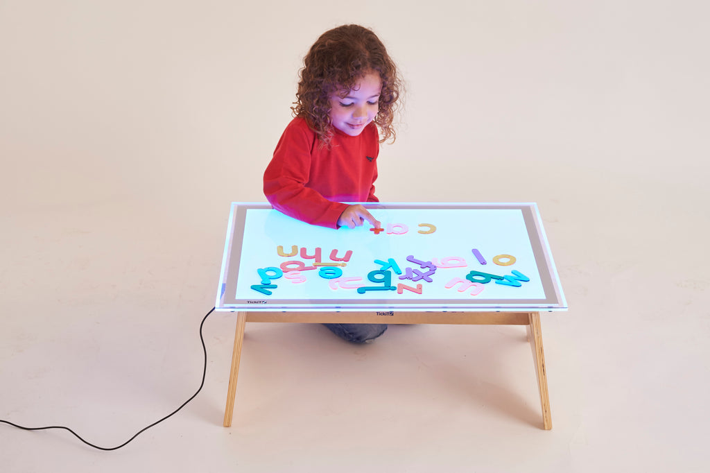 Rainbow letter activity board with colorful letters on a wooden stand